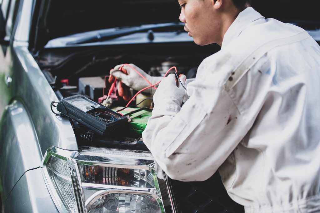 car repairman wearing a white uniform standing and holding a wre